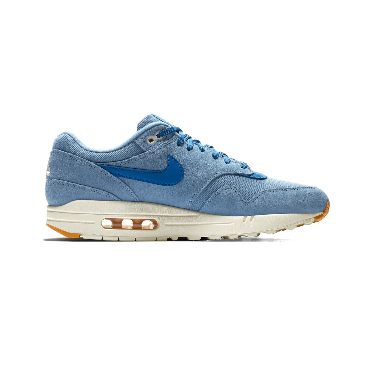 Side profile of a single light blue Nike Air Max 1 sneaker with a darker blue Swoosh, blue laces, and a cream midsole showing a visible orange-tinted Air window, toe pointing left.