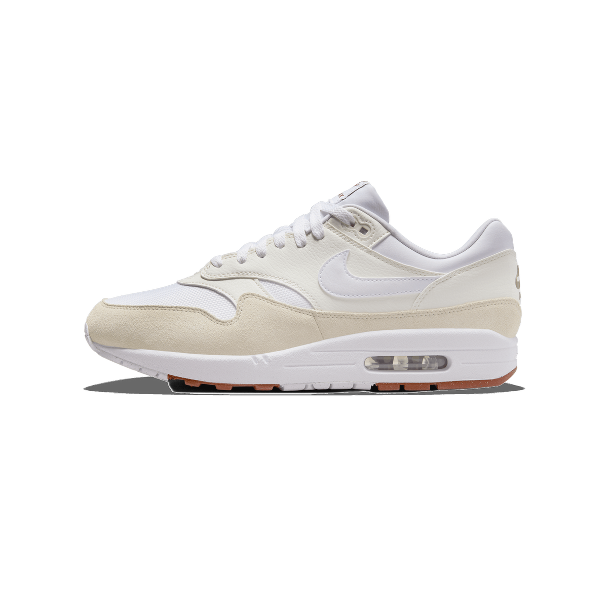 A single white and beige Nike Air Max 1 sneaker shown from the outside, toe pointing left, with white laces, a white Swoosh on the sail-coloured leather upper, beige suede toe and heel panels, a white midsole, and a visible clear Air unit with brown