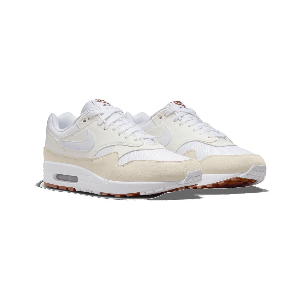 A pair of white and beige Nike Air Max 1 SC sneakers shown side by side, angled towards the left, with white laces, a white Swoosh on the sail-coloured upper, beige suede toe overlays, and brown-accented outsoles visible.