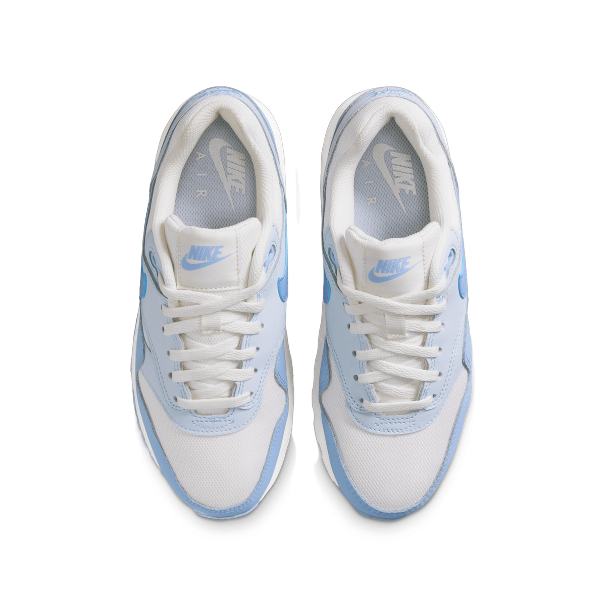 Top-down view of a pair of white and blue Nike Air Max 1 sneakers with blue Nike branding on the tongues and visible Air insoles.