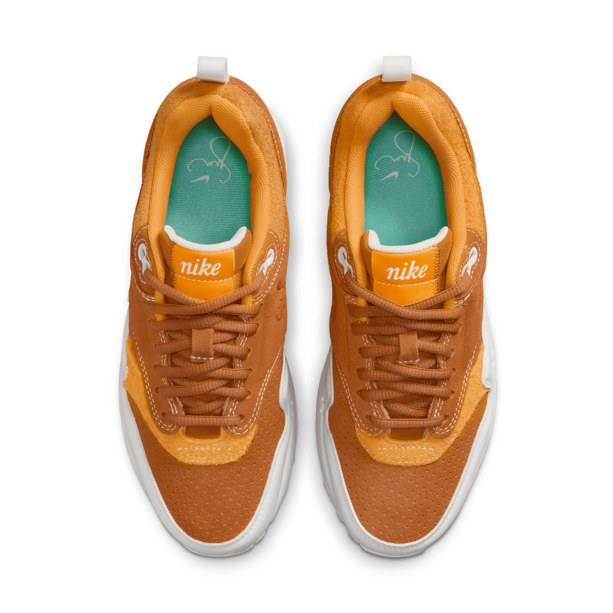 Top-down view of a pair of Nike Air Max 1 sneakers in brown and gold suede with white soles and green signature-print insoles