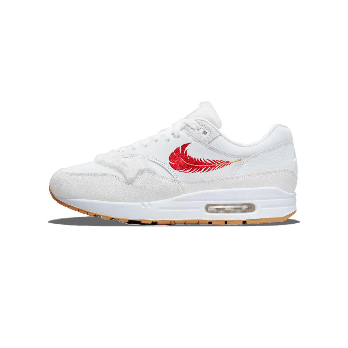 Side profile of a white Nike Air Max 1 with a red feather-style Swoosh embroidered on the side panel, white fur-like trim along the collar and tongue, grey suede toe and mudguard, and a visible clear Air unit in the white midsole with a gum rubber ou