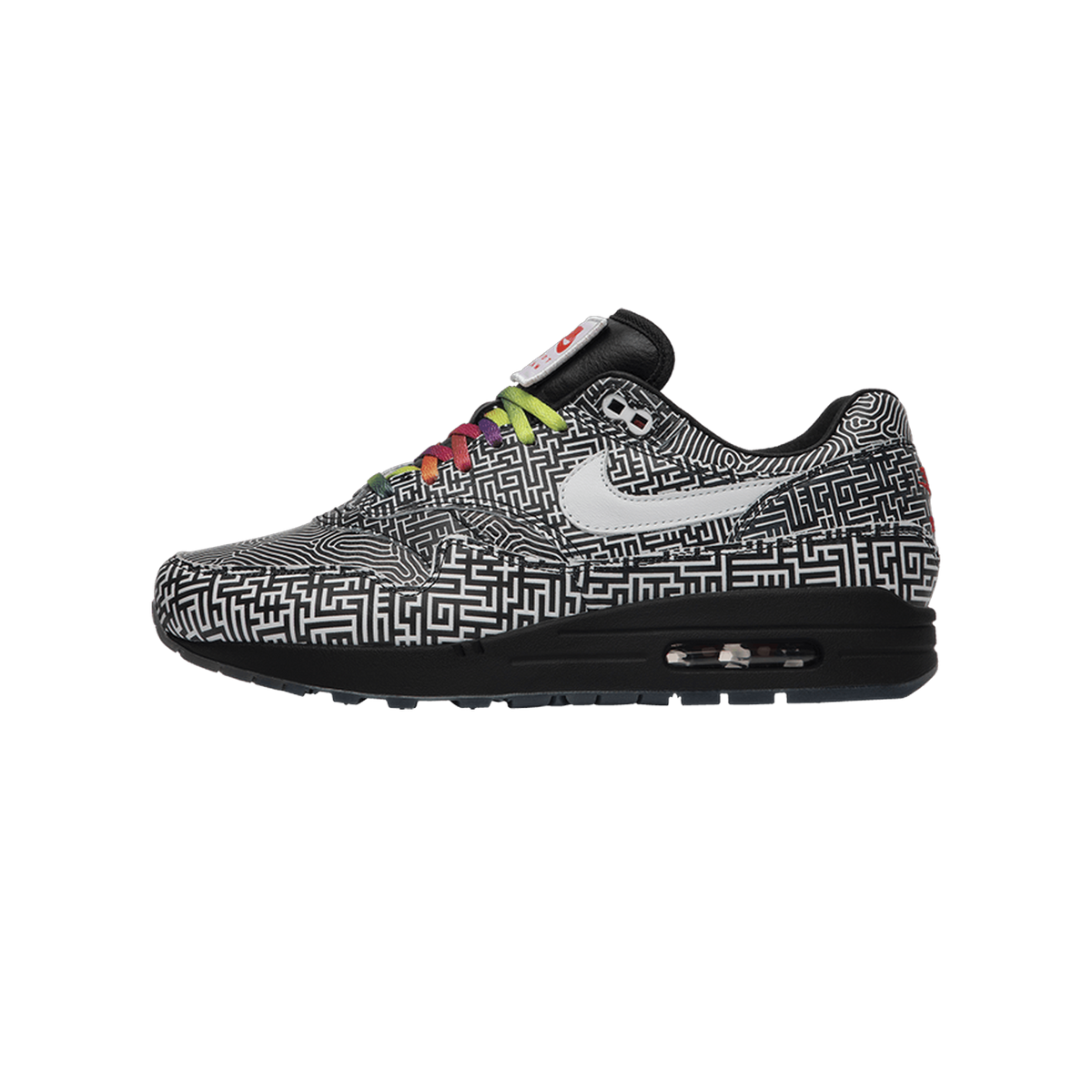 Side view of a Nike Air Max 1 sneaker with a black and white maze print, white swoosh, multicolor laces, and black midsole with visible air unit, toe pointing left