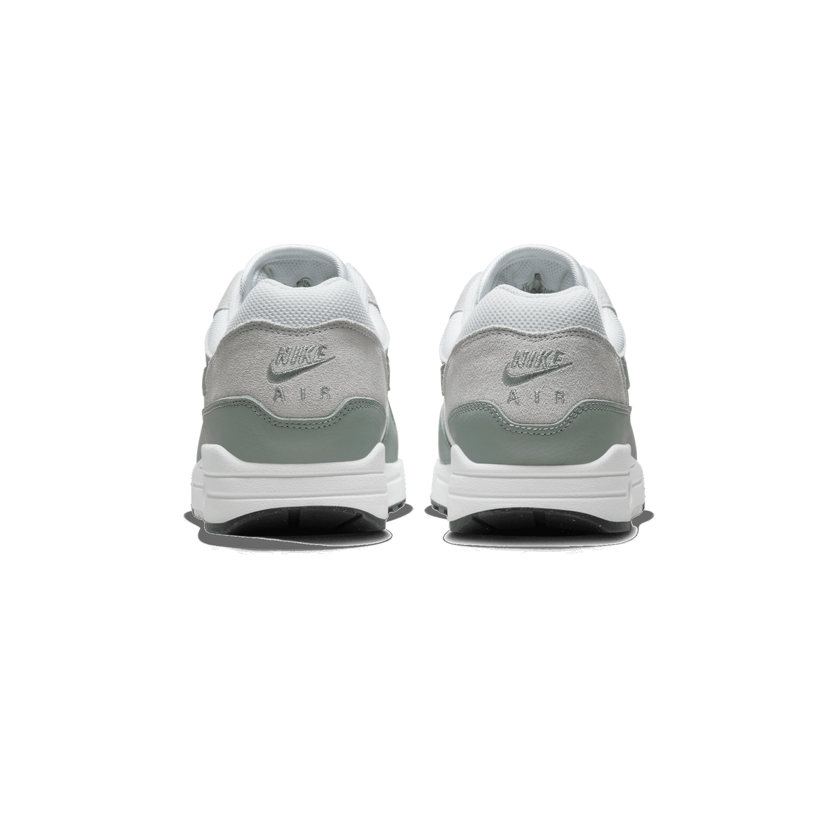 Rear view of a pair of white Nike Air Max 1 sneakers with grey suede heel panels, green accents, embroidered Nike Air logos, and white midsoles with visible Air cushioning.