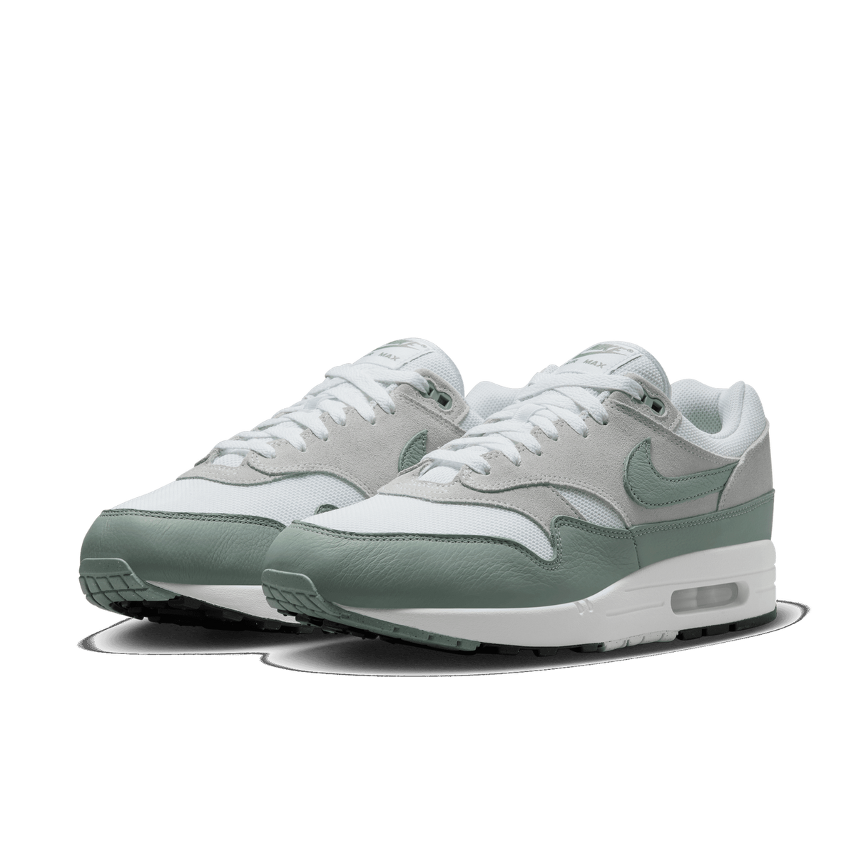 Pair of Nike Air Max 1 sneakers in white and mica green, shown angled toward the front with visible Swoosh logos and Air Max heel cushioning.