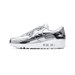 Side view of a Nike Air Max 90 sneaker in metallic silver with a white midsole and visible Air cushioning unit, toe pointing left