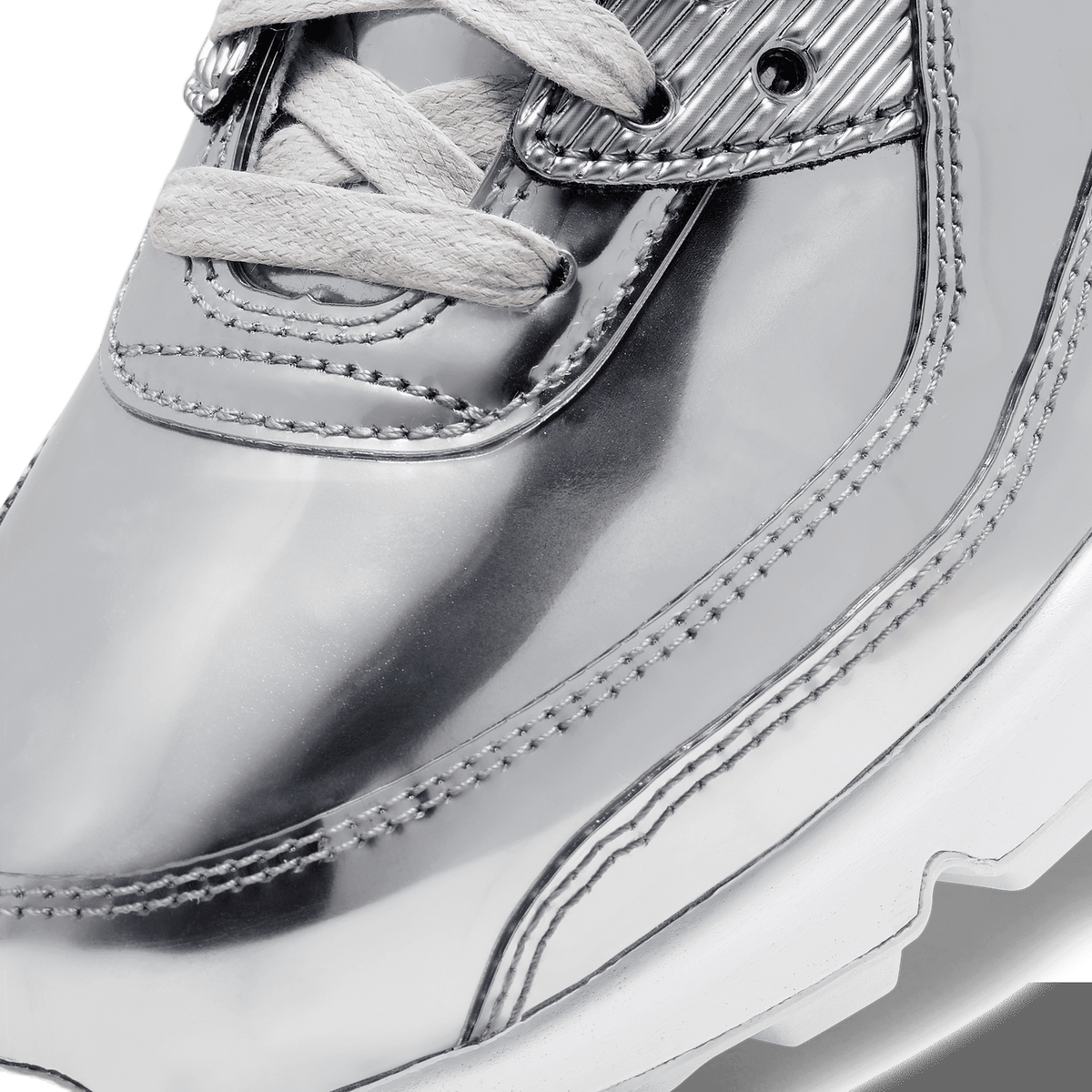 Close-up of a metallic silver Nike Air Max 90 toe box with white laces and visible stitching detail.
