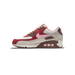 Left Nike Air Max 90 sneaker shown from the side with toe pointing left, featuring red, cream, brown and pink panels and a pink swoosh logo