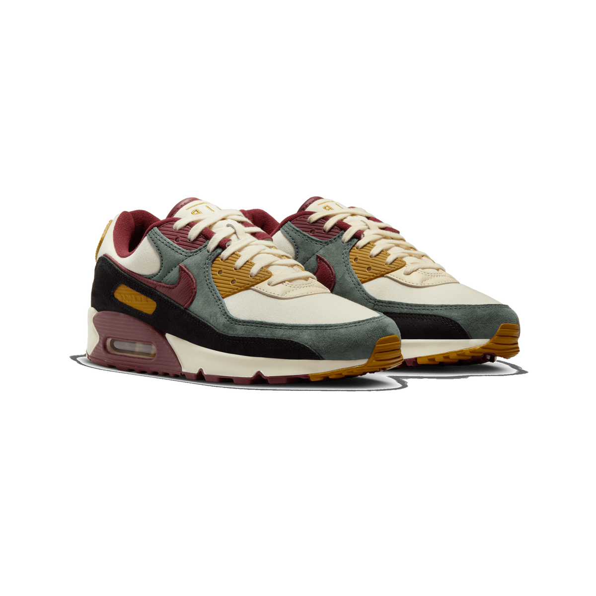 Pair of Nike Air Max 90 Premium sneakers in cream, sage green, burgundy, black, and mustard yellow, angled toward the left front.