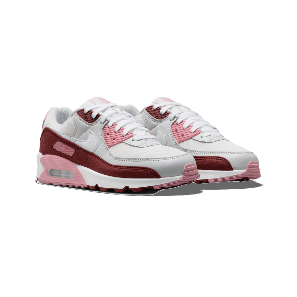 A pair of white, pink and dark red Nike Air Max 90 sneakers shown side by side at a three-quarter angle on a white background, with visible white laces, pink tongue and heel accents, dark red suede panels, and a pink Air Max window on the midsole.