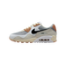 Left Nike Air Max 90 SP Patta sneaker shown from the outside with toe pointing left, featuring grey mesh, white overlays, tan accents, black swoosh, and a visible Air unit in the heel.