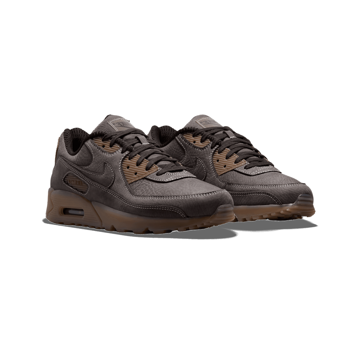 Pair of brown Nike Air Max 90 sneakers with textured leather uppers, tan corduroy accents, dark laces, and a translucent brown outsole, shown at an angled front view.