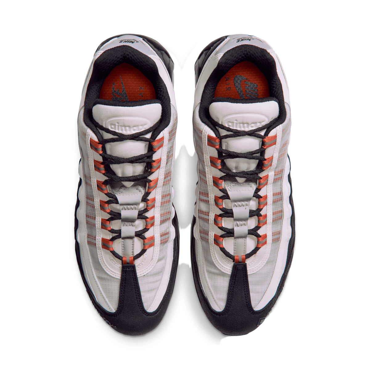 Top-down view of a pair of Nike Air Max 95 GORE-TEX sneakers in white and black with orange accents on the laces and orange interior lining, toes pointing downward and upward.