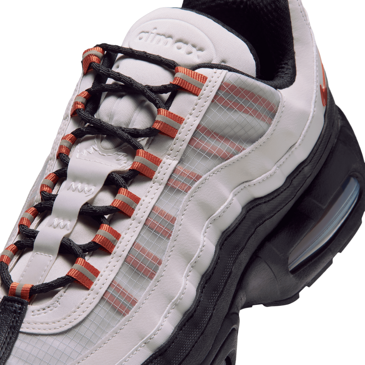 Close-up of a Nike Air Max 95 GORE-TEX sneaker showing the black laces with orange accents, ripstop panel, and visible air unit in the black midsole