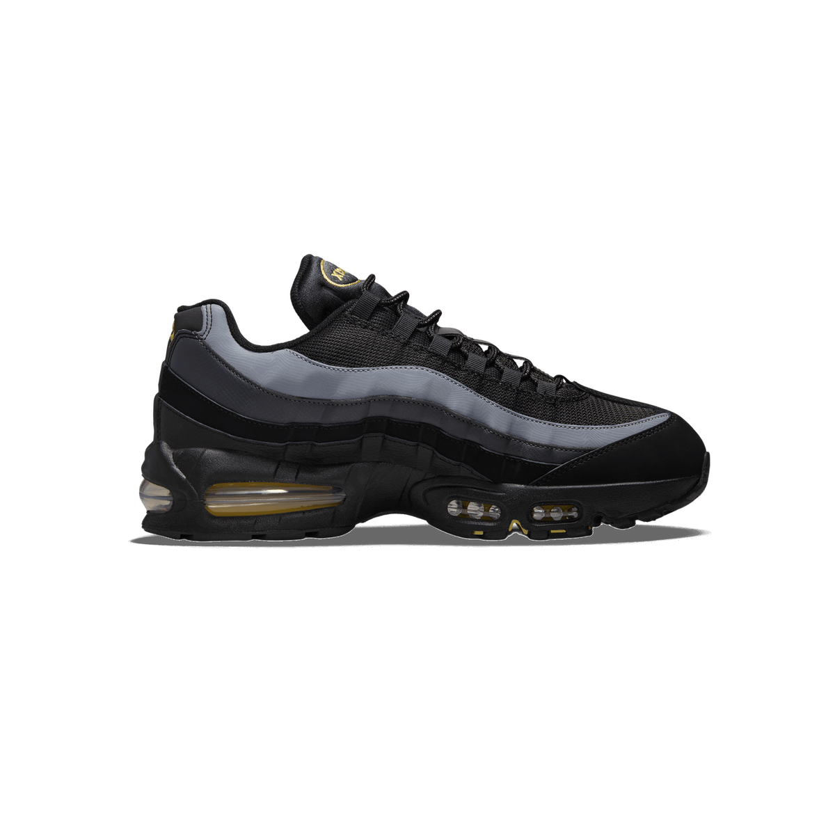 Side profile of a black and grey Nike Air Max 95 sneaker with the toe pointing left, showing the yellow Nike logo on the tongue, grey mesh overlays, and visible yellow-tinted Air units in the midsole.
