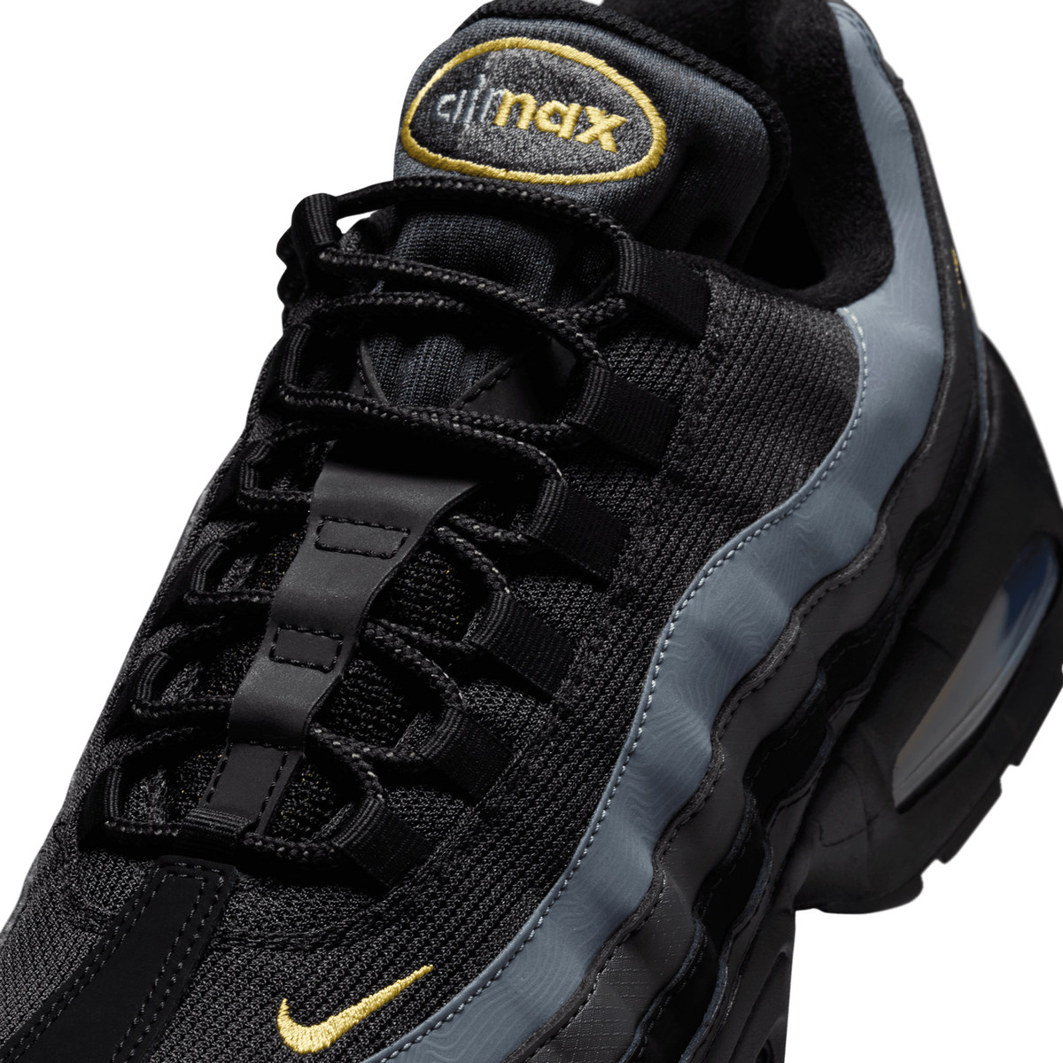 Close-up of the black and grey Nike Air Max 95 tongue and lacing, showing the embroidered gold 'air max' logo on the tongue, a gold Swoosh on the mesh upper, and grey overlay panels along the side.