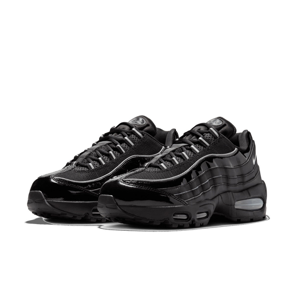 A pair of black patent leather Nike Air Max 95 sneakers shown side by side at a three-quarter front angle, with glossy black overlays, grey mesh panels, and a visible grey Air unit in the heel.