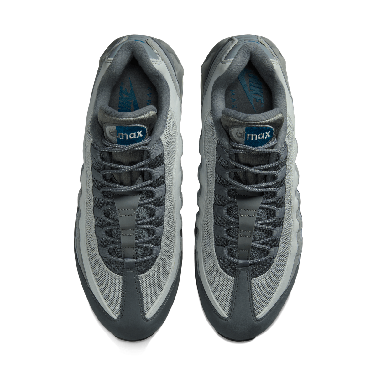 Overhead view of a pair of grey Nike Air Max 95 sneakers placed side by side with toes pointing up, showing the laced tongues, grey mesh panels, and blue-green Nike and Air Max branding inside the collars.