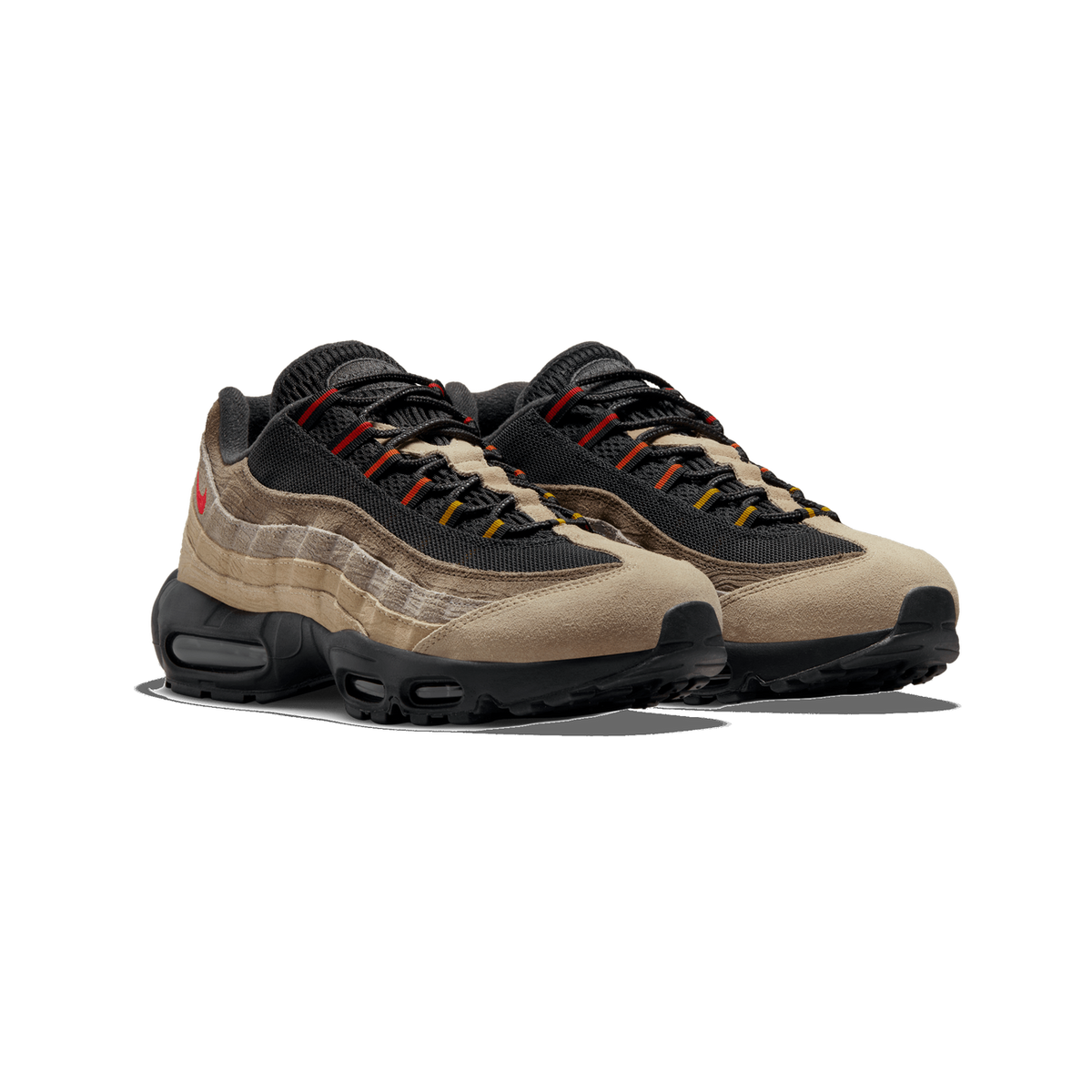 A pair of Nike Air Max 95 sneakers angled toward the left, showing beige suede toes, black mesh panels, brown and tan layered overlays, red and yellow lace accents, and a black Air Max sole.