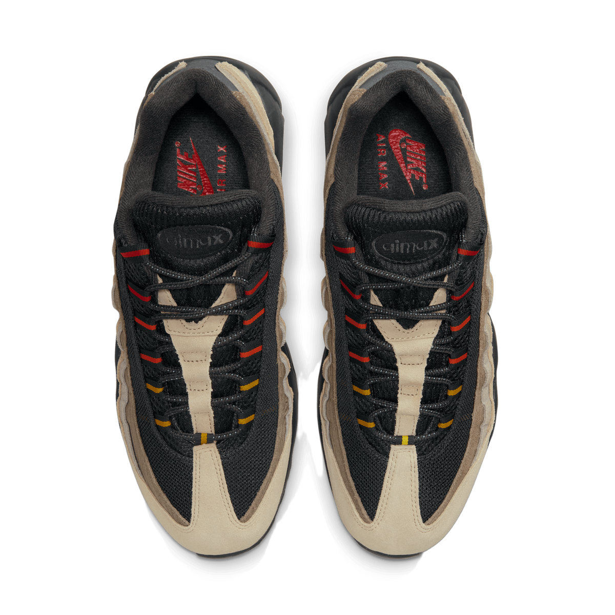 Overhead top-down view of a pair of black, gray, and beige Nike Air Max 95 sneakers placed side by side, showing the tongues, laces with red and yellow accents, and red Nike Air Max logos on the insoles.