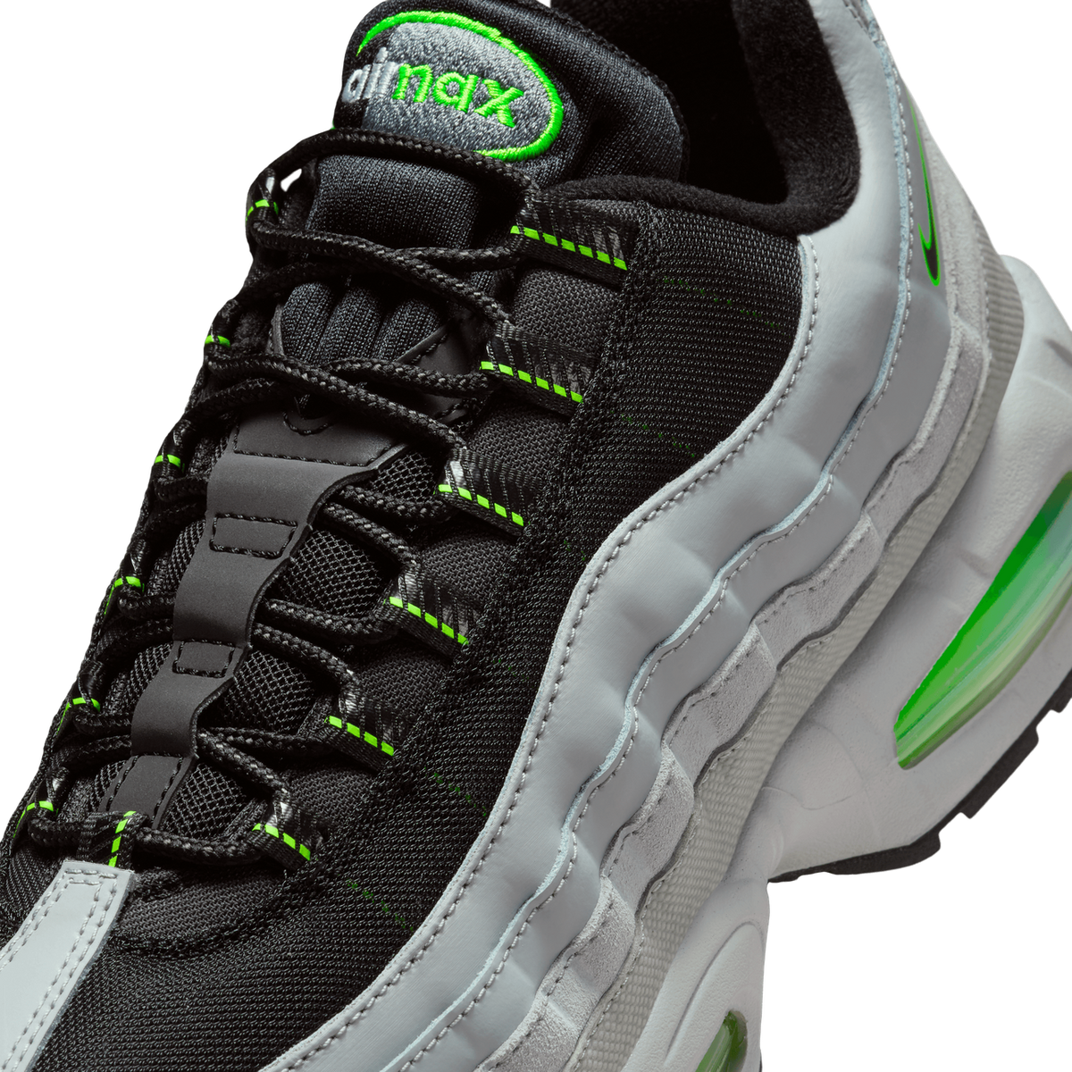 Close-up detail of a Nike Air Max 95 showing the black mesh upper with grey overlays, neon green stitching and Swoosh, the 'air max' heel tab embroidery, and the visible neon green Air unit in the midsole.