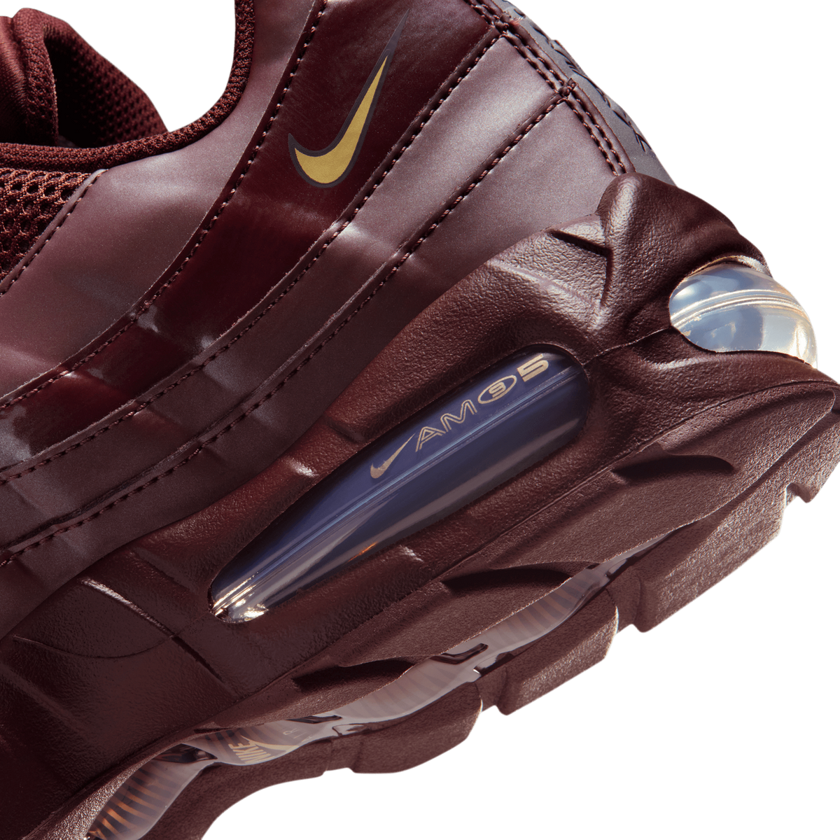 Close-up of the heel and side of a burgundy Nike Air Max 95 showing a gold Swoosh logo on the upper, a visible clear Air unit with 'AIR MAX 95' text in the midsole, and the textured burgundy heel.