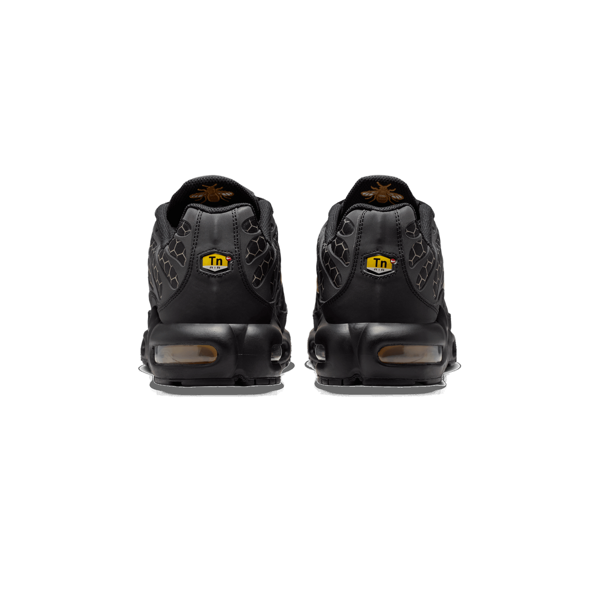 Rear view of a pair of black Nike Air Max Plus sneakers showing the Tn Air heel tabs, honeycomb overlay pattern, and visible air cushioning units in the soles.