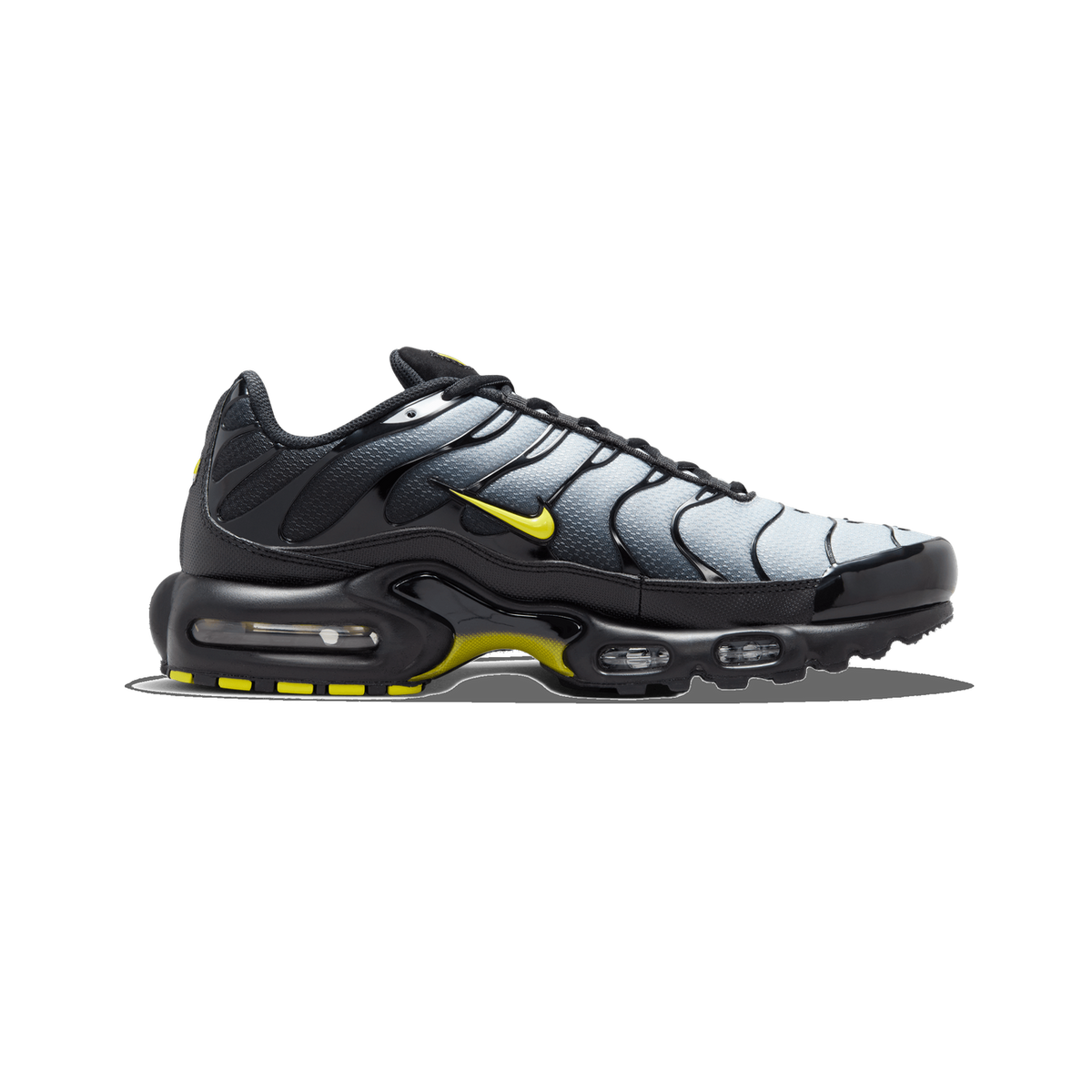 Left Nike Air Max Plus shoe facing left, with a grey wavy mesh upper fading to black, yellow Swoosh, and yellow accents on the black outsole