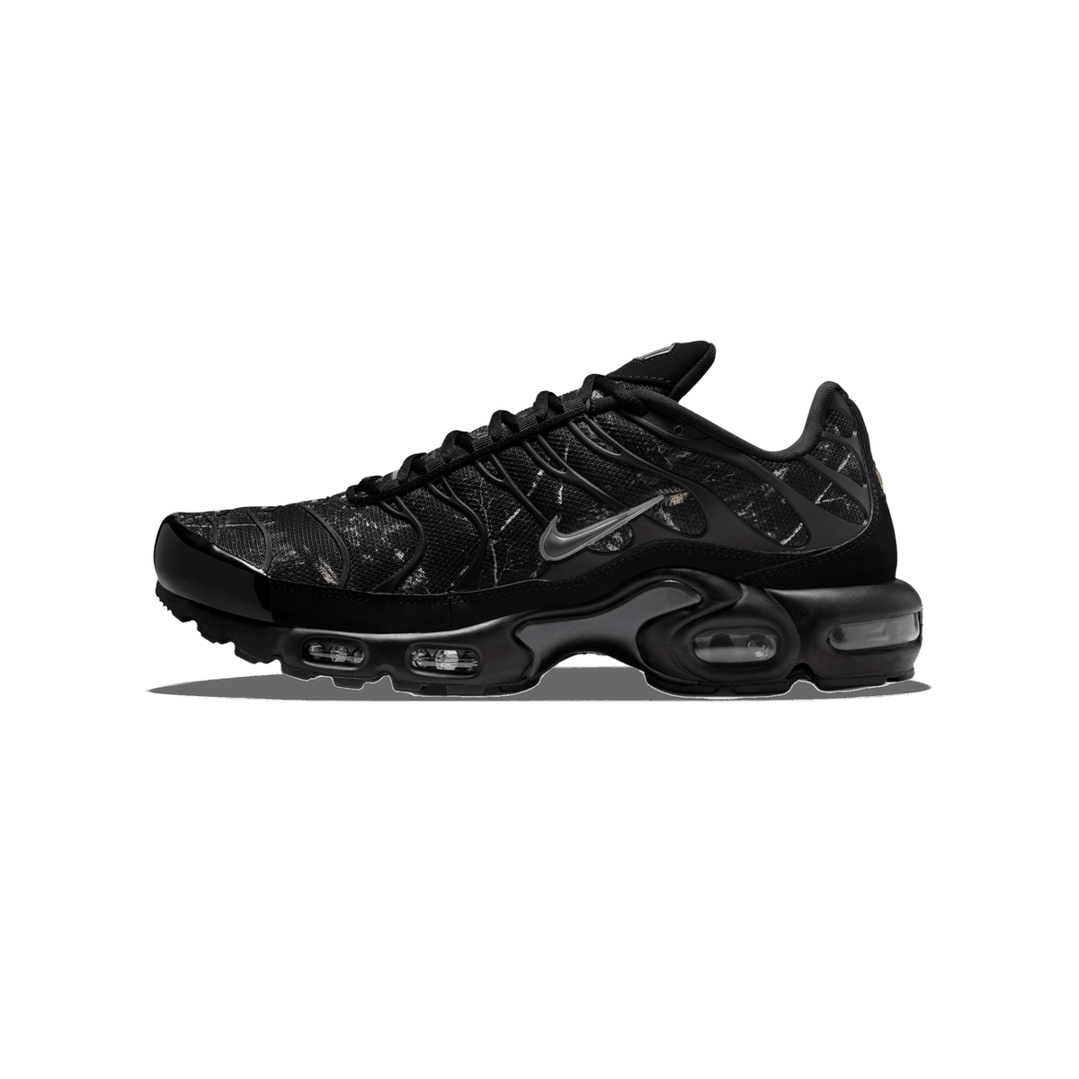 Side view of a black Nike Air Max Plus sneaker with a subtle wood camo print on the upper and a grey swoosh, toe pointing left.