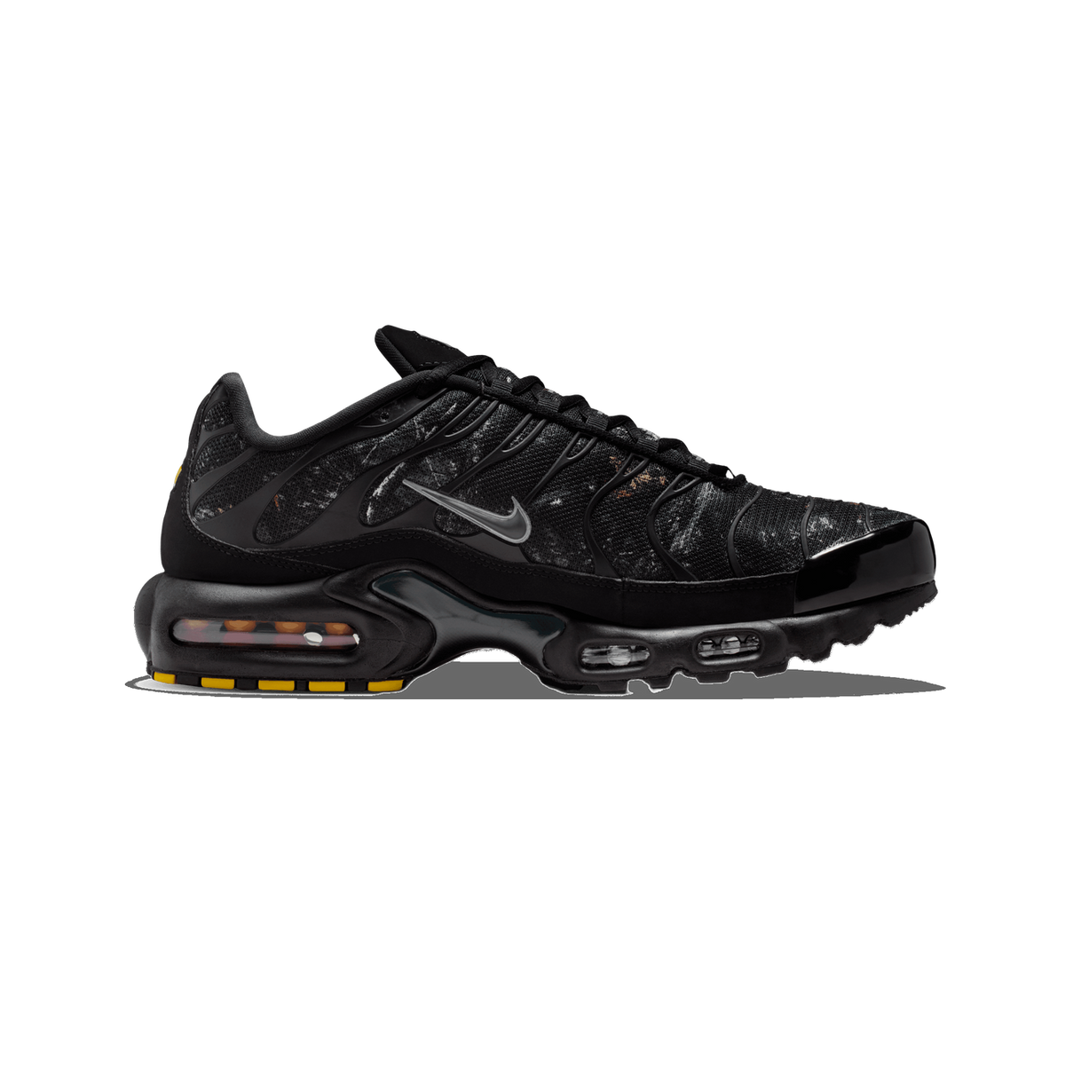 Lateral view of a black Nike Air Max Plus with a mottled grey and orange textured upper, grey swoosh, and visible air cushioning unit in the sole with yellow outsole accents, toe pointing left.