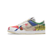 Side view of a left Nike Dunk Low sneaker with a multicolor patchwork design featuring burlap, blue, green, yellow and red panels and a tan swoosh with '2.2 LBS' text, toe pointing left.