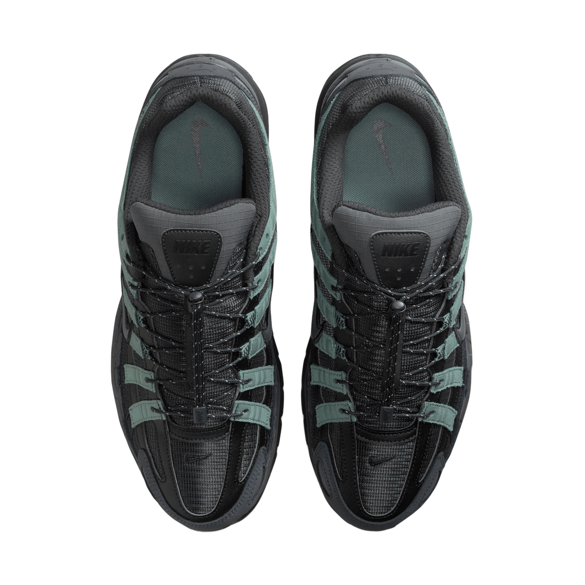 Top-down view of a pair of black and grey Nike P-6000 sneakers with green suede overlays, toes pointing up, showing the tongues with Nike branding, the bungee-style lace toggles, and the insoles.