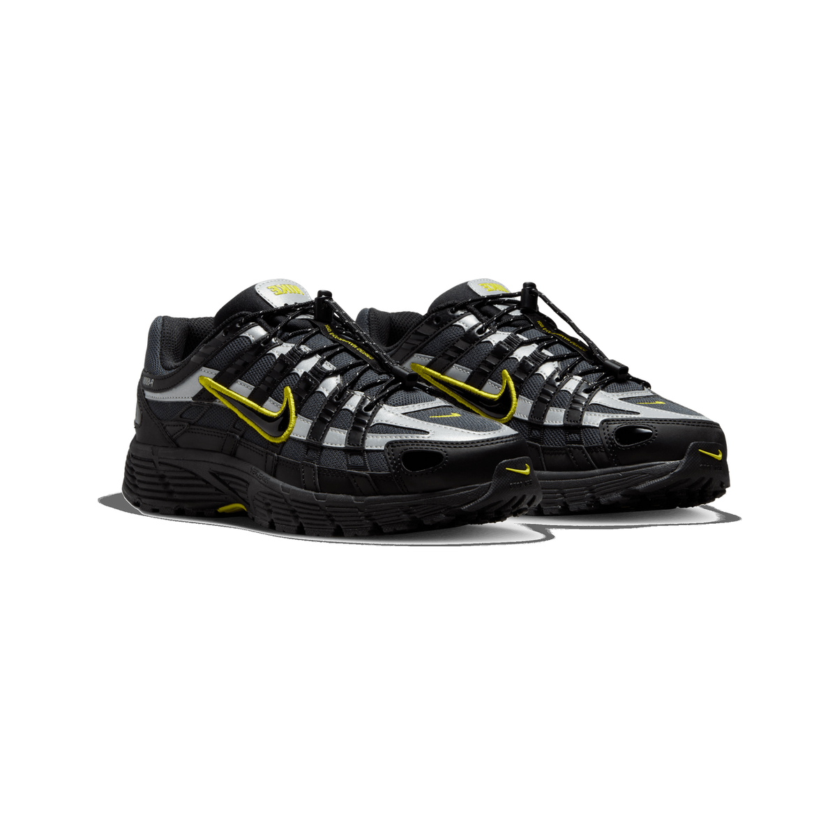 A pair of black, grey and yellow Nike P-6000 sneakers shown side by side at a three-quarter front angle, with yellow Swoosh logos, silver reflective overlays and black toggle lacing visible.