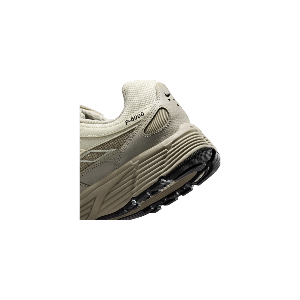 Close-up rear heel view of a beige Nike P-6000 sneaker showing the ridged midsole, black outsole tread, and P-6000 text branding.