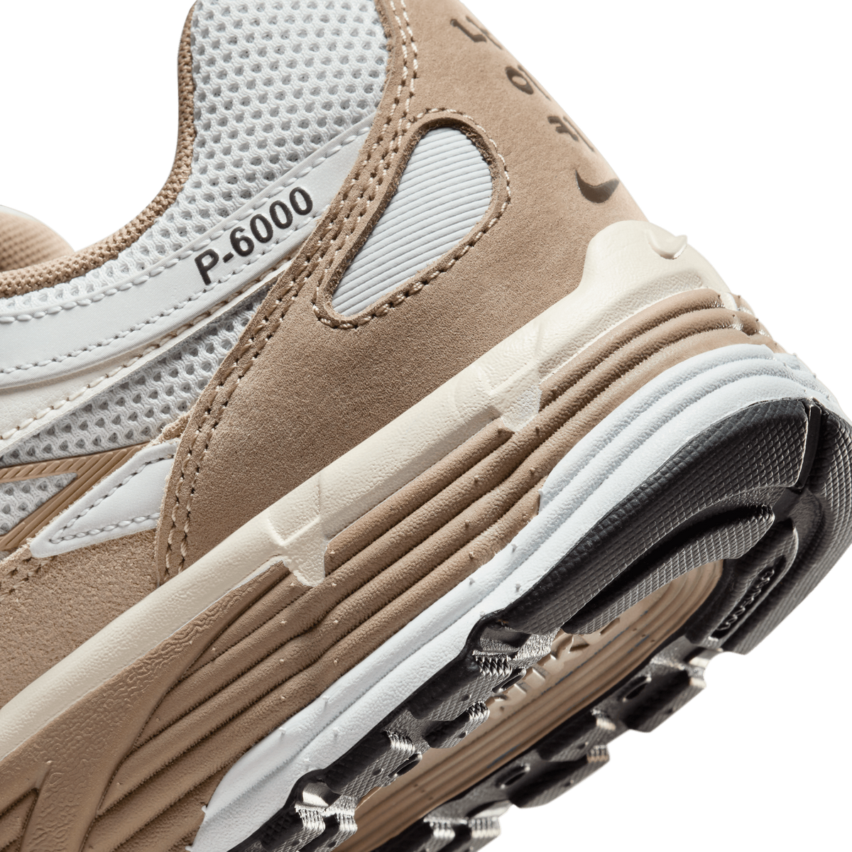 Close-up of the heel and lateral side of a beige suede and white mesh sneaker showing the P-6000 text on the mesh panel, a Nike Swoosh on the heel, and the layered white and black rubber outsole edge.