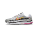 Side view of a white and silver Nike P-6000 sneaker with a pink and yellow-outlined swoosh, black mesh panels, and a pink midsole accent, toe pointing left.