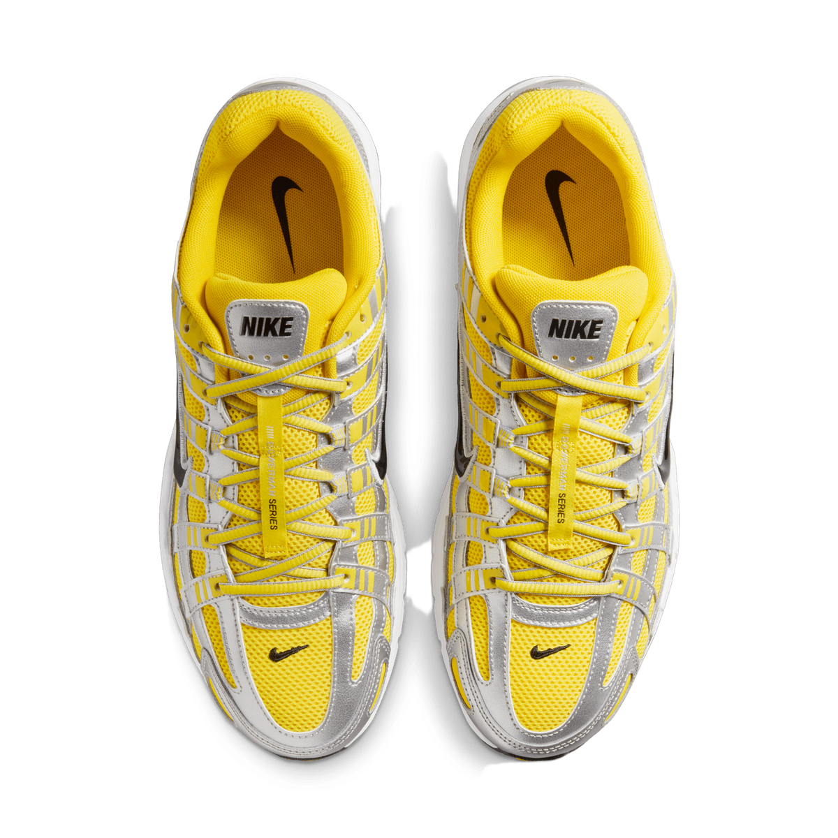 Overhead top-down view of a pair of yellow and silver Nike P-6000 sneakers placed side by side on a white background, showing the laces, tongues with Nike branding, and metallic silver overlays.