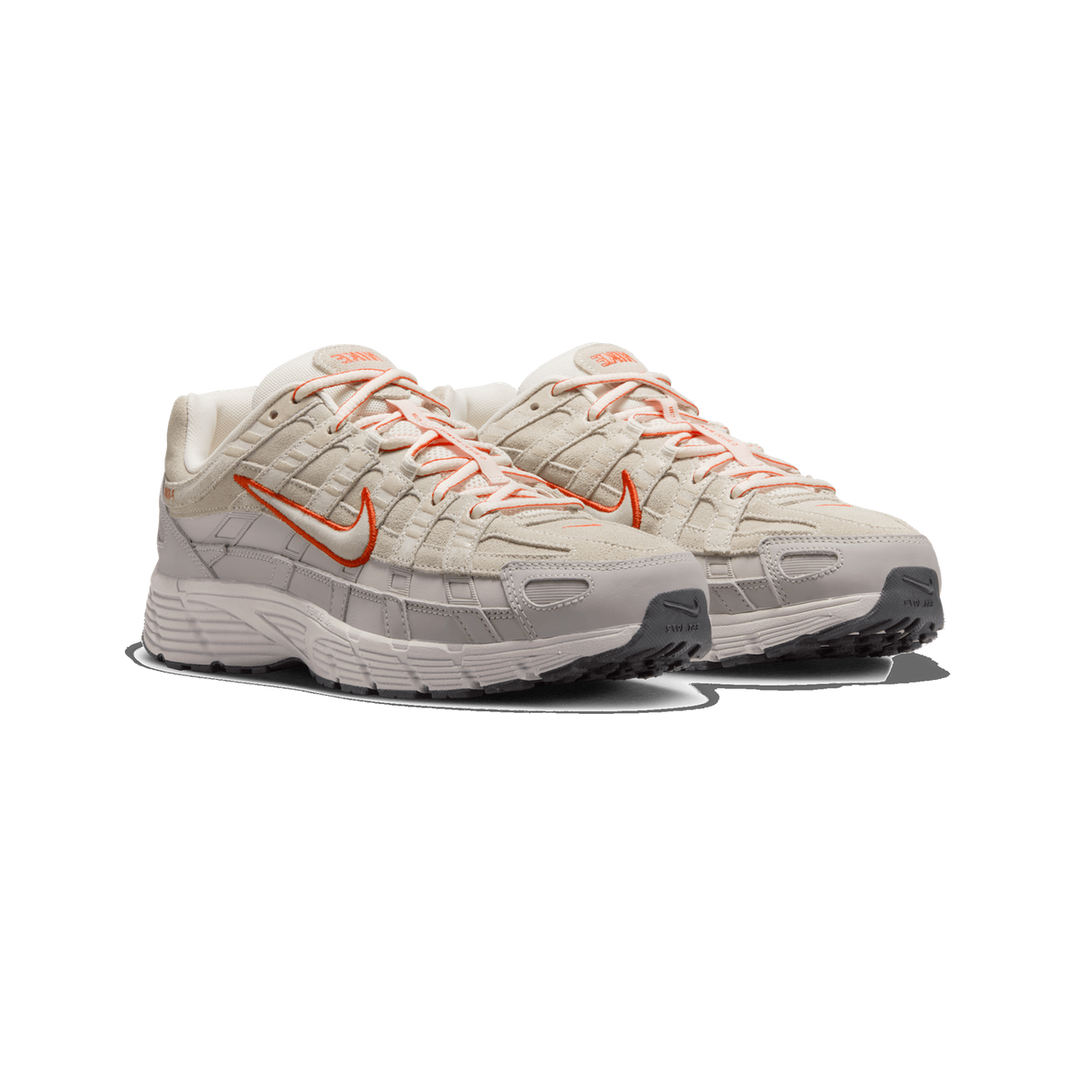 A pair of cream and light grey Nike P-6000 sneakers angled side by side, showing orange-outlined Swoosh logos on the sides, orange laces, and grey rubber soles.
