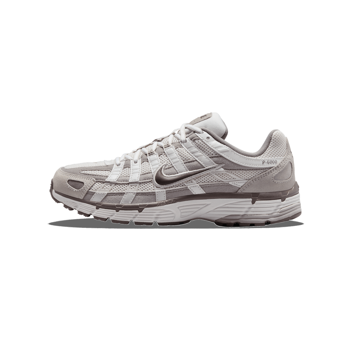 Side profile of a single Nike P-6000 sneaker with the toe pointing left, showing a light beige and taupe mesh and suede upper, brown Swoosh logo, and P-6000 branding on the heel.