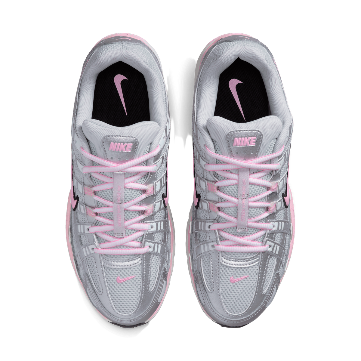 Top-down view of a pair of Nike P-6000 sneakers in silver and grey with pink laces, pink Nike swoosh logos, and black tongue inserts with pink Nike branding.