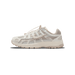 Side profile of a cream and beige Nike P-6000 sneaker with the toe pointing left, showing the embroidered Swoosh logo, bungee lace toggles, and a chunky off-white sole.