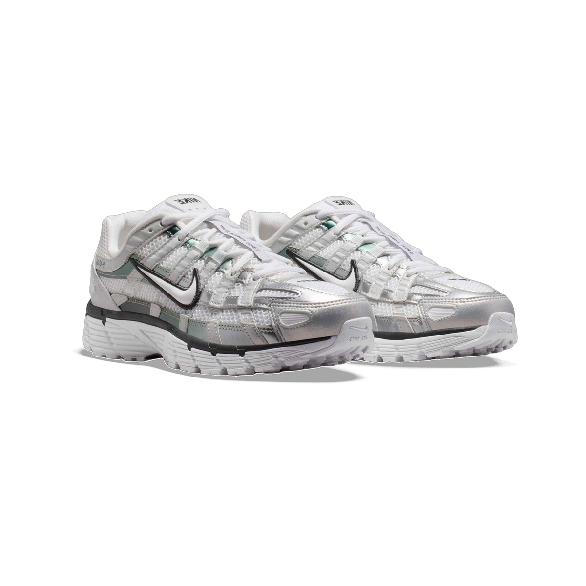 Pair of Nike P-6000 sneakers in white and metallic silver with black swoosh logos, layered mesh panels, and chunky white outsoles, shown at a front-angled view