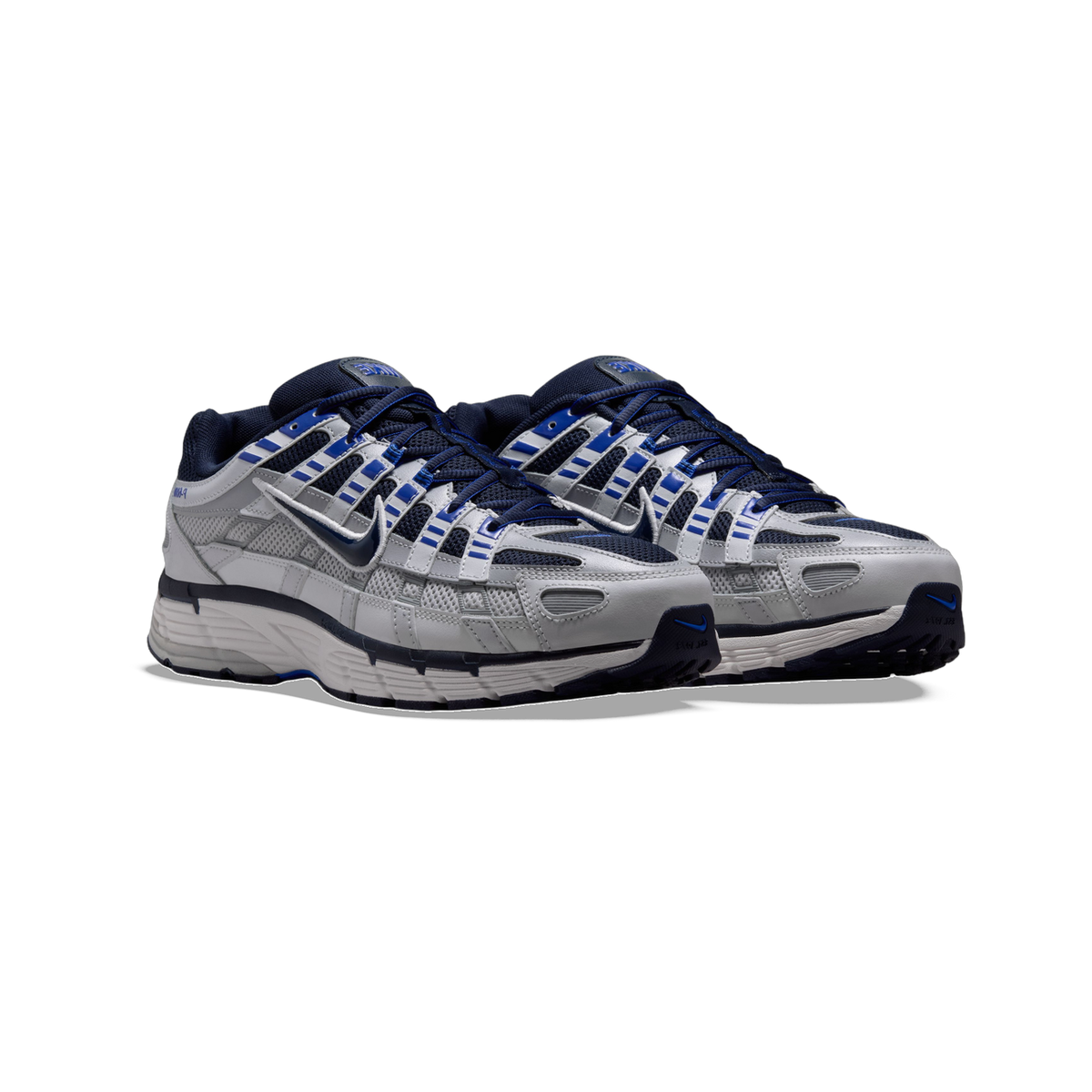 Front-angled view of a pair of Nike P-6000 sneakers in grey, navy, and blue with layered mesh panels and chunky ridged soles.
