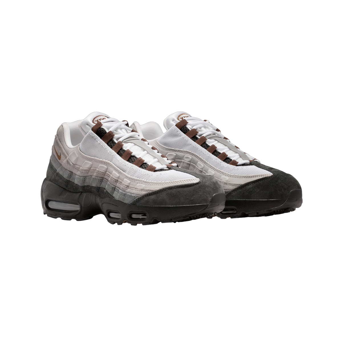 Pair of Nike Air Max 95 sneakers in white, grey, and black with brown accent laces and dark suede toe caps, shown at a front angle.