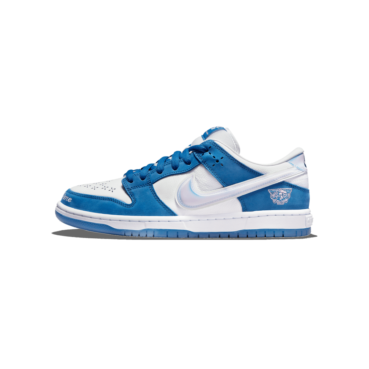 Lateral view of a blue and white Nike SB Dunk Low with an oversized white Swoosh outline, embroidered crest logo, and translucent blue outsole, toe pointing left.