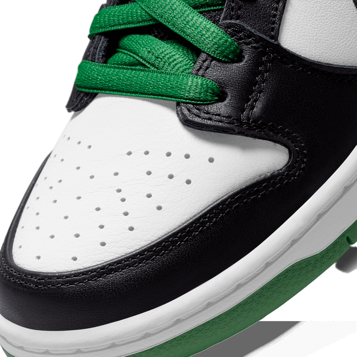 Close-up of the toe box of a white and black Nike SB Dunk Low with green laces and a green midsole stripe, showing perforated leather detailing.