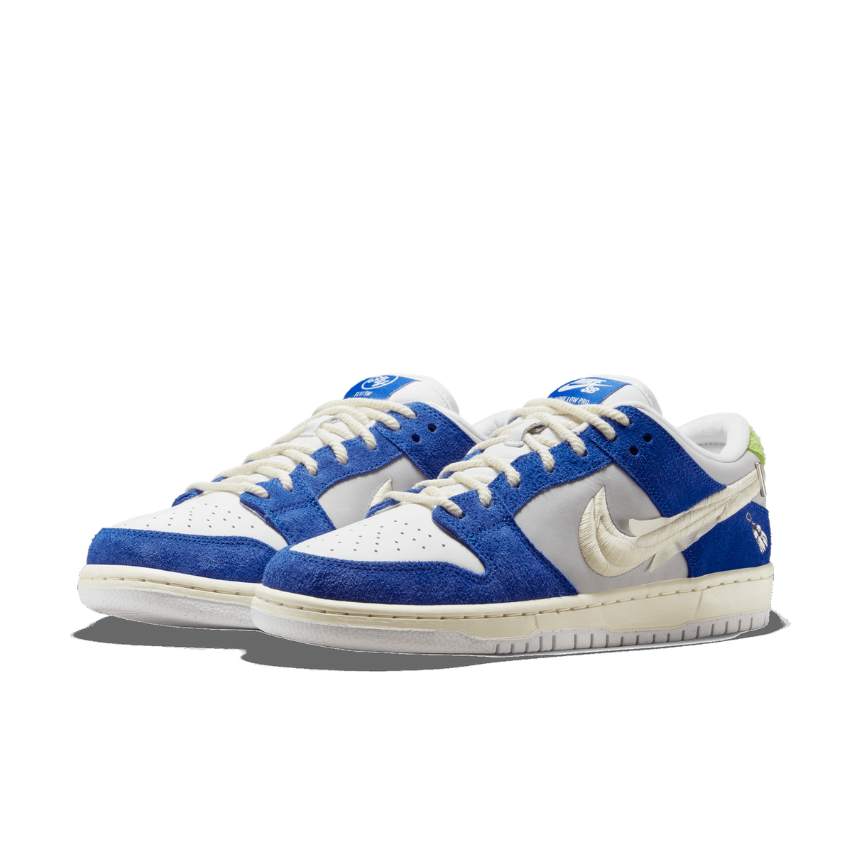 Pair of Nike SB Dunk Low sneakers in blue suede and grey leather with cream Nike SB swoosh logos and off-white laces, angled toward the front-left