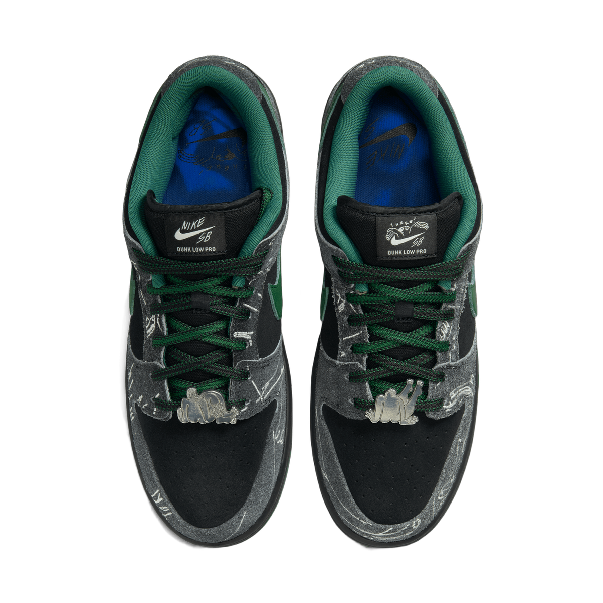 Top-down view of a pair of Nike SB Dunk Low sneakers in black, grey, and green with metallic figure charms on the laces and blue branded insoles.