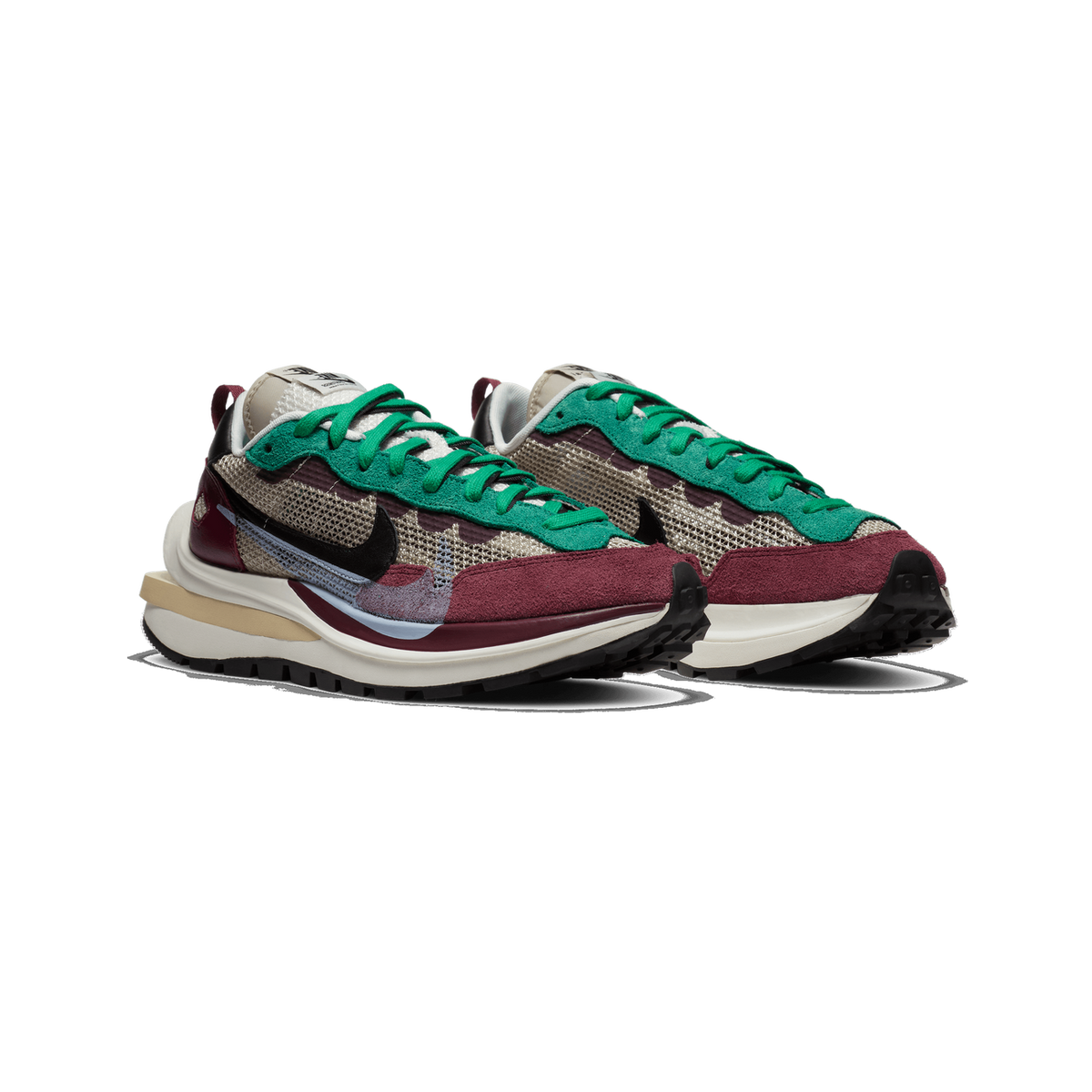 A pair of Nike sacai sneakers shown side by side at an angle, with green laces and suede overlays, burgundy suede and leather accents, a beige mesh upper, black swoosh logos, and a cream and tan midsole with black tread.