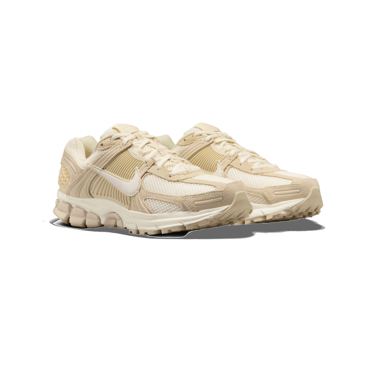 Pair of Nike Zoom Vomero 5 sneakers in cream, beige, and tan, shown side by side angled toward the left, with white laces and a visible Nike swoosh on each shoe.